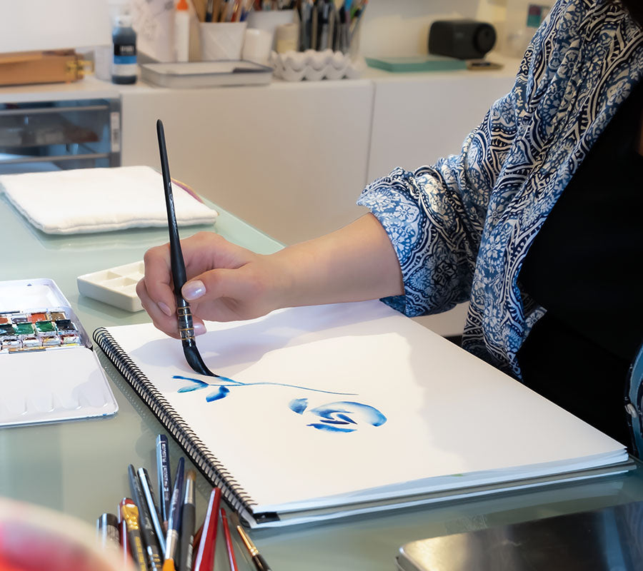 close up image of jenny painting in blue watercolor