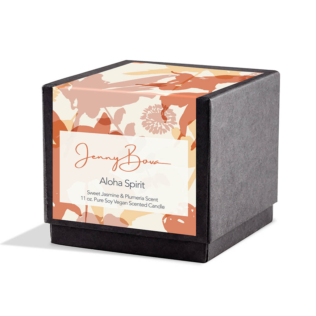 Square black candle box with a label covering front and top. The label is a peach, pink and orange silhouetted floral. On the front are the Jenny Bova logo, the name of the candle, &quot;Aloha Spirit” and product details. The background is white.