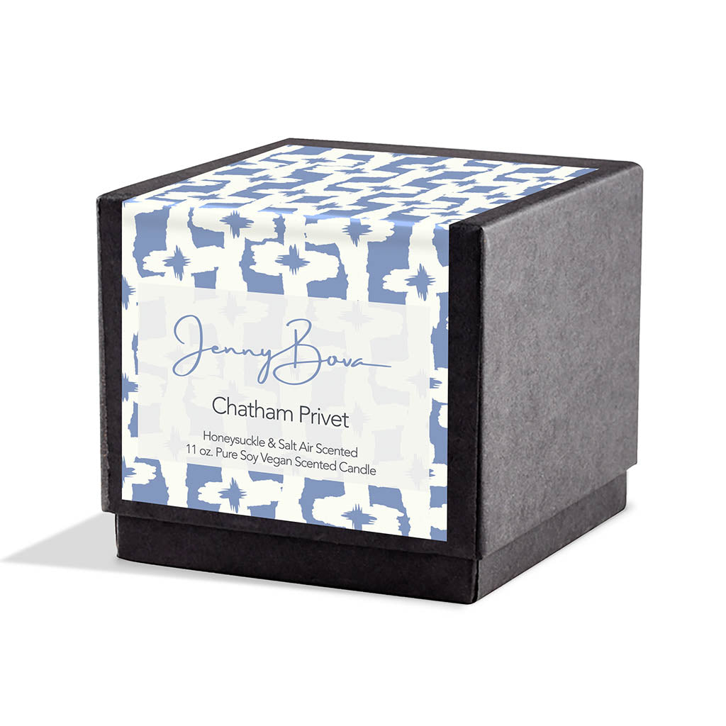 Square black candle box with a label covering front and top. The label is a blue and white geometric design. On the front are the Jenny Bova logo, the name of the candle, &quot;Chatham Privet,” and product details. The background is white. 