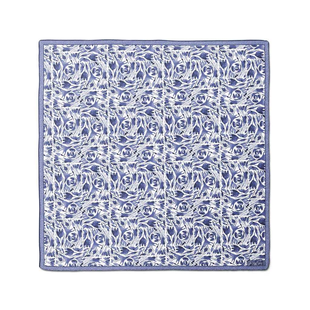 Image of a 26x26 square silk habotai scarf with an indigo blue watercolor design. Design has a folk feel with repeating squares of florals and dots. Jenny Bova logo in the lower right corner