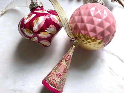 hand-painted glass Christmas ornaments with ribbons and beads. Ornaments have pink, gold, maroon, and white patterns