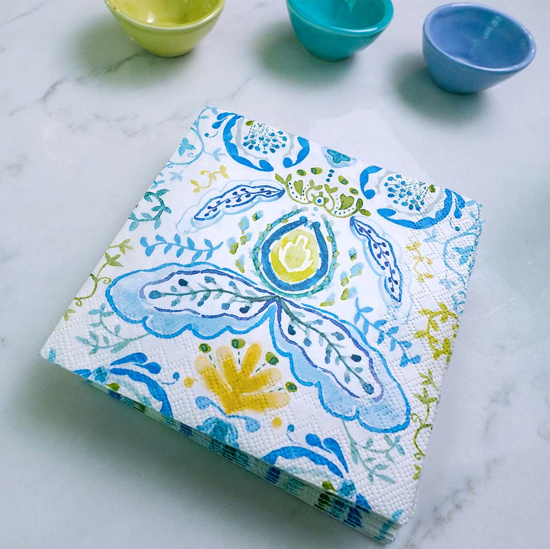Pack of decorative paper towels with floral pattern on a marble surface with small bowls.