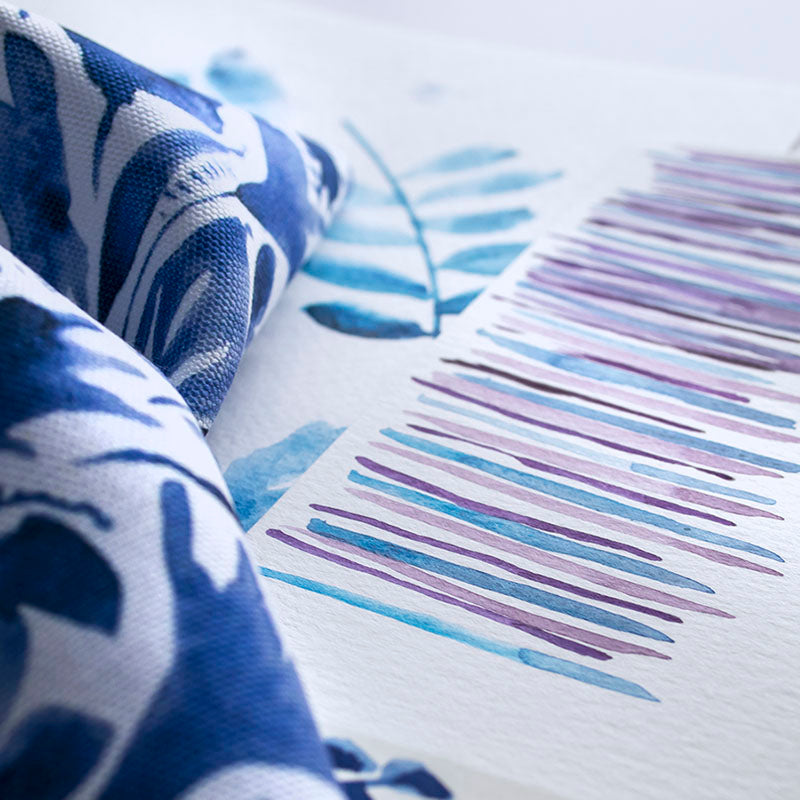 blue and purple watercolor paintings next to printed fabric in blue and white