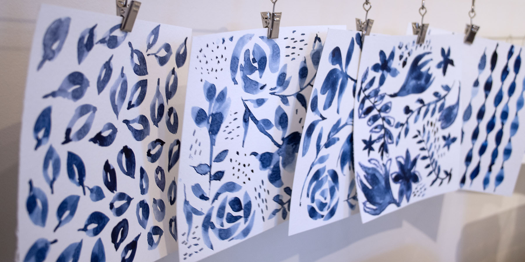 small blue watercolor paintings in floral and abstract shapes on clips