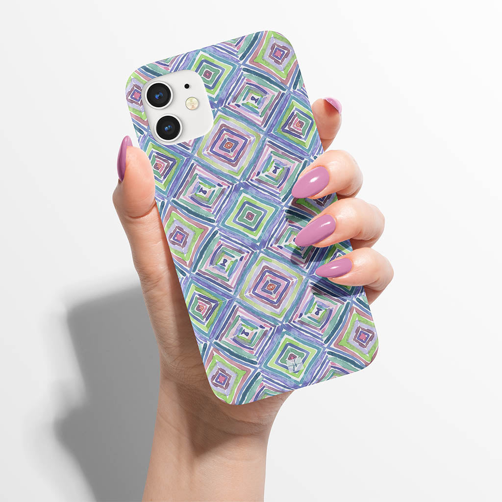 watercolor diamond repeat pattern in blues, greens, and purples on an iPhone case in a woman&#39;s hand