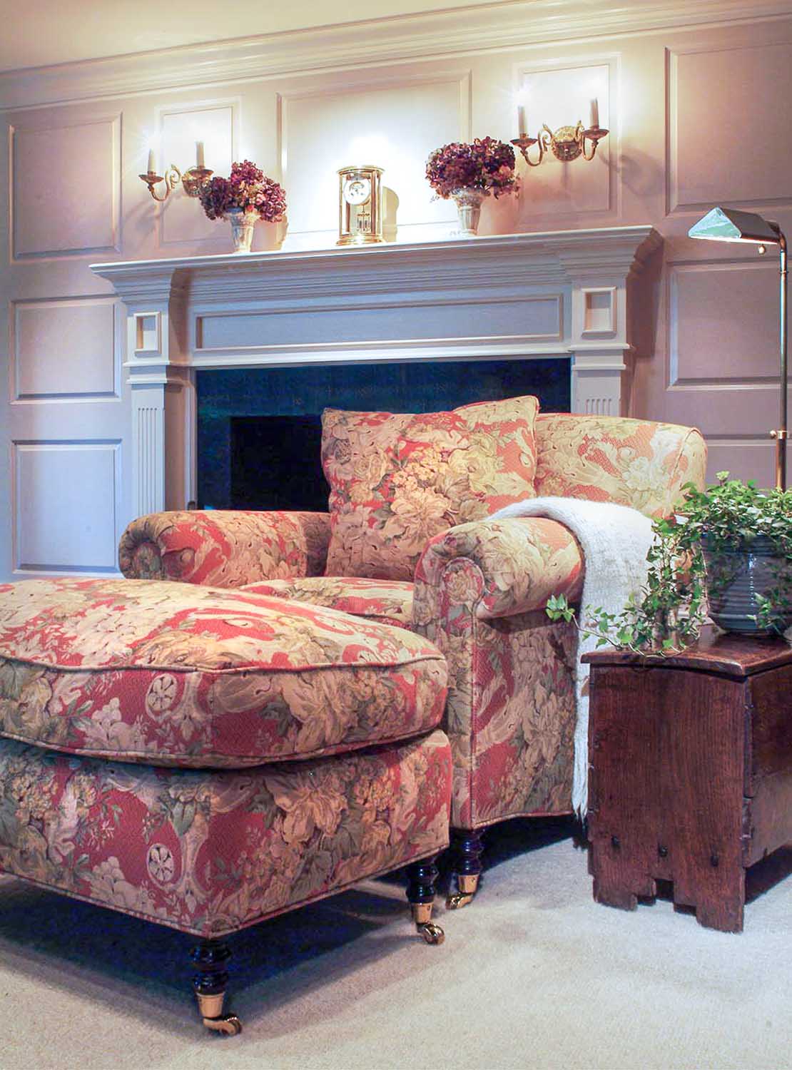 a classic english chair and ottoman in front of a fireplace. 