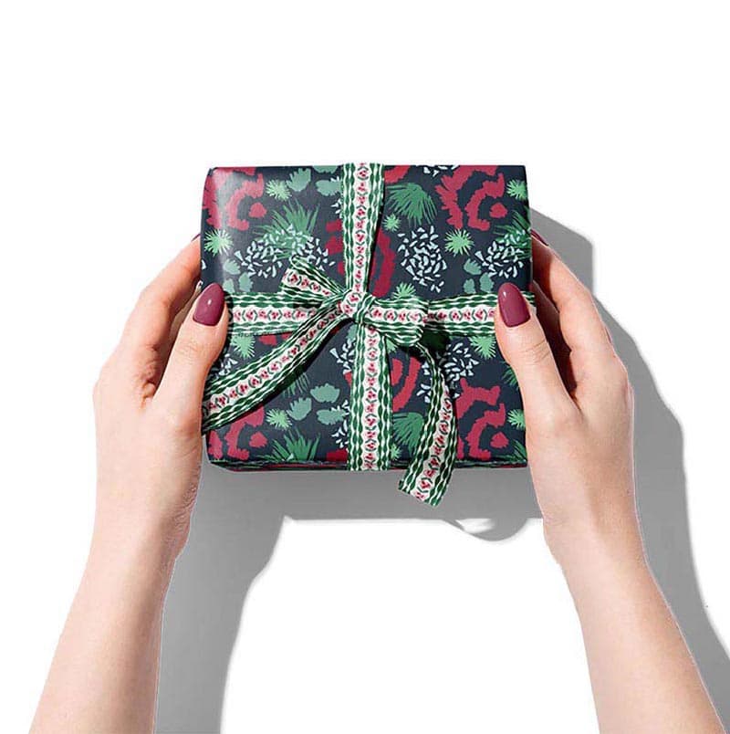 Christmas gift wrap shown on a box in a woman's hands