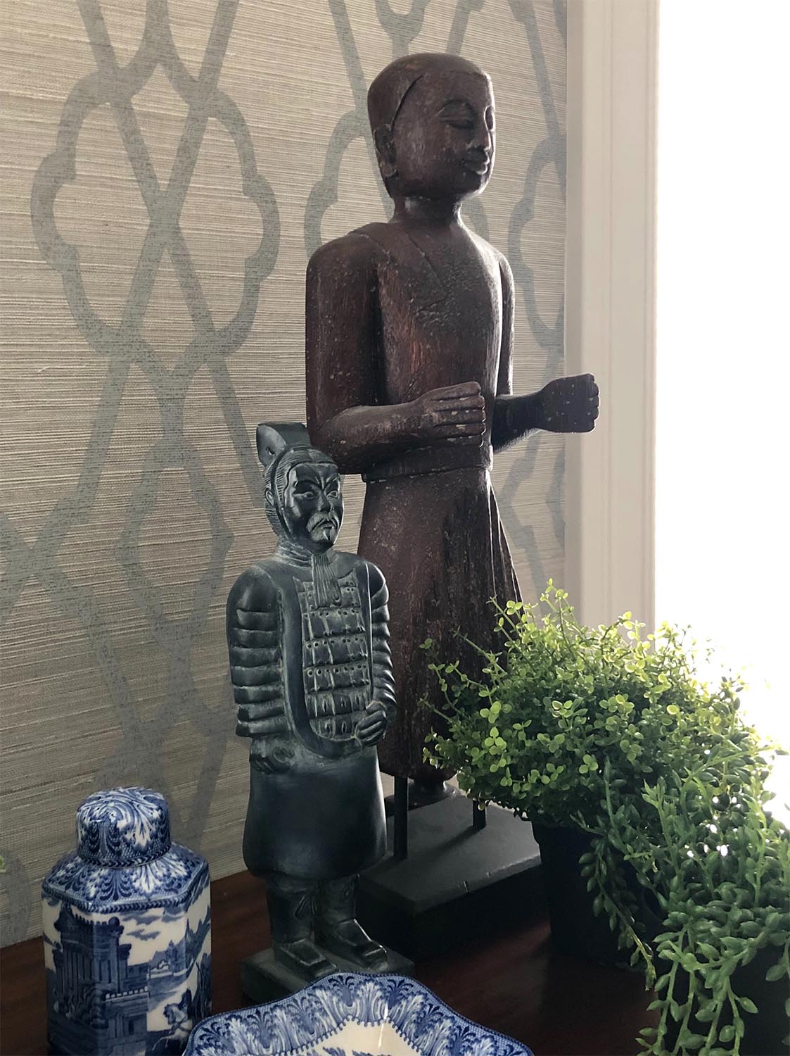 Asian statues with blue and white porcelain and geometric grasscloth wallpaper 