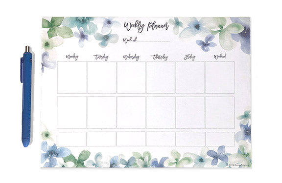 Watercolor weekly planning page shown with pen next to it