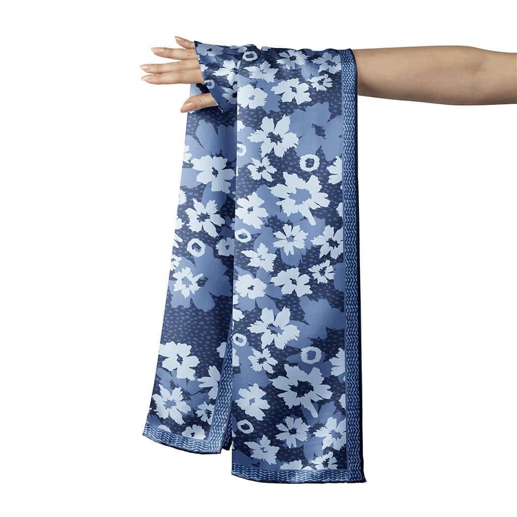 16x72 inch silk habotai scarf draped over a womans hand. Scarf design is floral with textural patterns in shades of blue. The flowers are abstact, bold, and modern. 