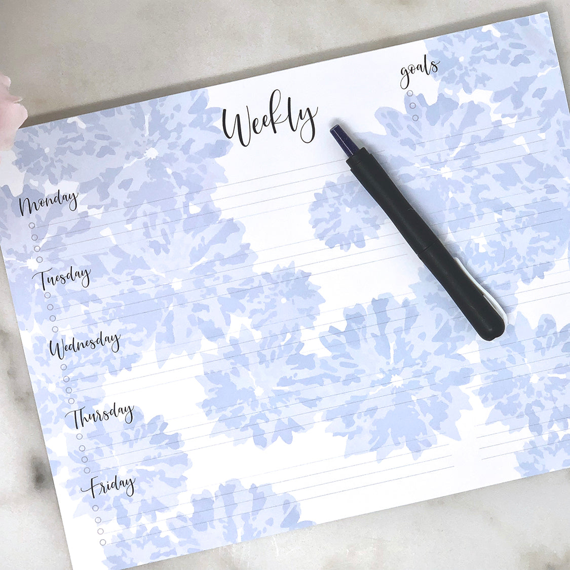 Weekly notepad blue on white with black type in use